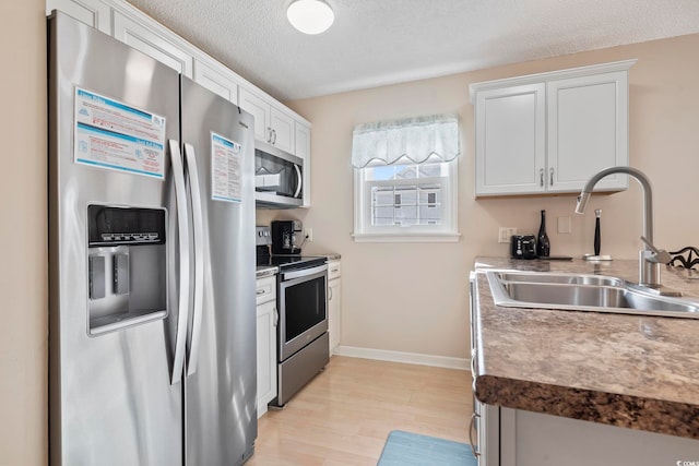 1425 N Waccamaw Dr Unit 123, Garden City Beach, SC 29576 - kitchen featuring stainless steel appliances, a sink, light wood-type flooring, white cabinets, and baseboards