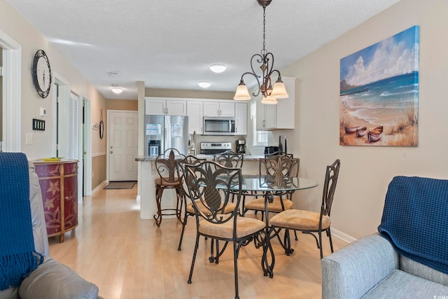 1425 N Waccamaw Dr Unit 123, Garden City Beach, SC 29576 - dining room with light wood-style flooring, a textured ceiling, baseboards, and a chandelier