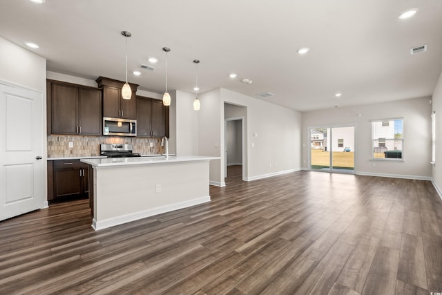 kitchen featuring stainless steel appliances, tasteful backsplash, dark brown cabinets, light countertops, and dark wood-style flooring