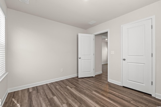 unfurnished bedroom with dark wood finished floors and baseboards