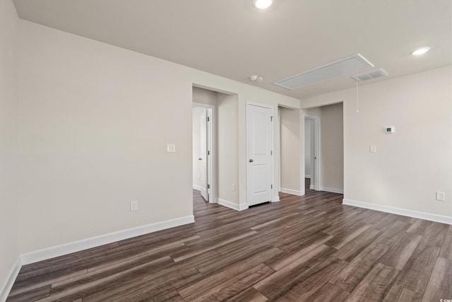 empty room with attic access, dark wood finished floors, baseboards, and recessed lighting