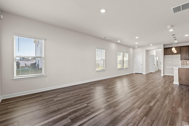 unfurnished living room with dark wood-type flooring, recessed lighting, and baseboards