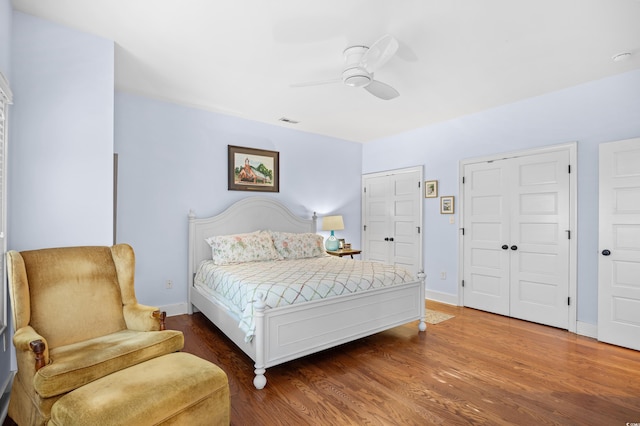 bedroom featuring ceiling fan, visible vents, baseboards, and wood finished floors
