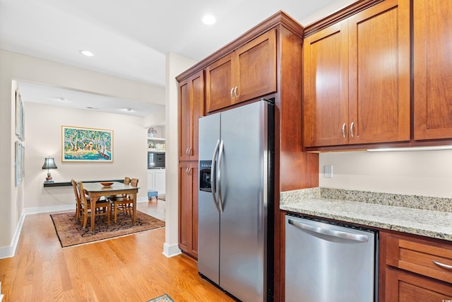 kitchen featuring light stone countertops, light wood-type flooring, recessed lighting, stainless steel appliances, and brown cabinets