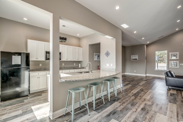 5504 Shelly Lynn Dr, Myrtle Beach, SC 29579 - kitchen with a sink, white cabinets, freestanding refrigerator, light wood finished floors, and a breakfast bar