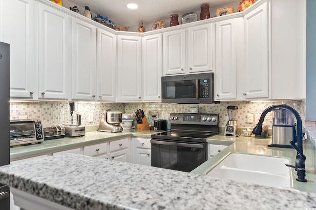 kitchen with electric stove, a sink, and white cabinets
