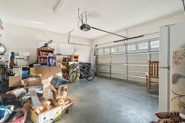 garage featuring a garage door opener and freestanding refrigerator