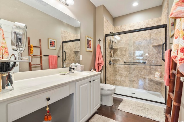 bathroom featuring hardwood / wood-style flooring, a shower stall, toilet, and vanity
