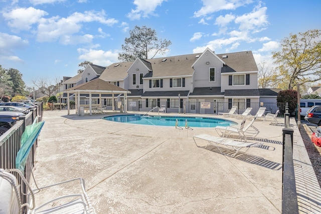 pool with a patio, fence, a gazebo, and a residential view