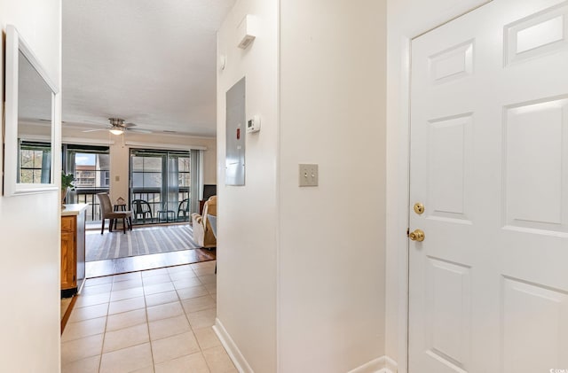 hall featuring baseboards and light tile patterned floors