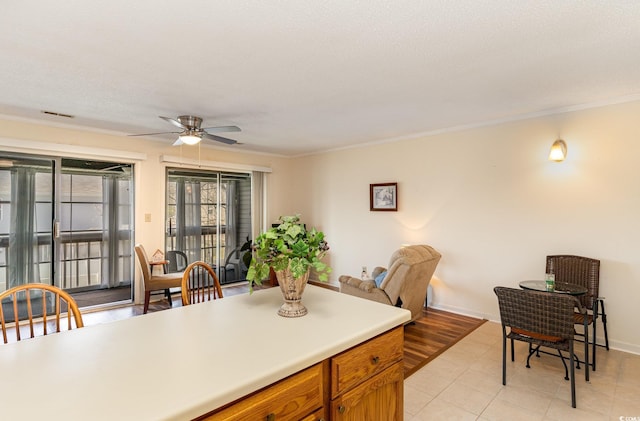 kitchen with crown molding, light countertops, brown cabinetry, visible vents, and ceiling fan
