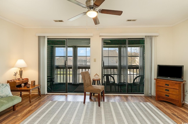 living area with plenty of natural light, crown molding, and visible vents
