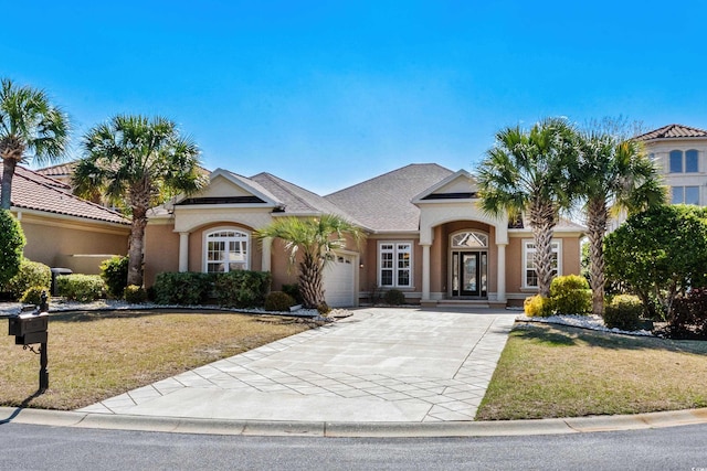 view of front facade with an attached garage, a front lawn, stucco siding, and driveway