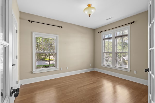 spare room with baseboards, wood finished floors, and visible vents