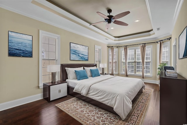 bedroom featuring baseboards, ornamental molding, dark wood-type flooring, and a raised ceiling