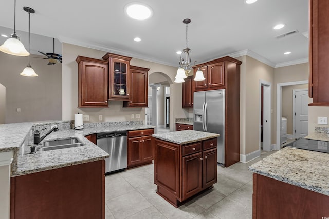 kitchen featuring stainless steel appliances, a sink, arched walkways, crown molding, and a peninsula
