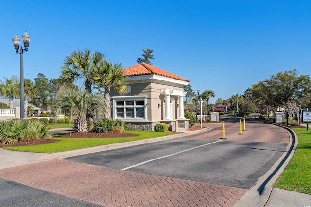 view of road with street lights, a gated entry, and curbs