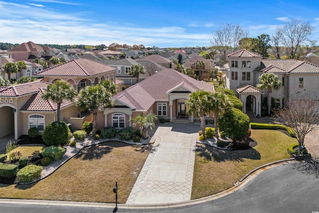 mediterranean / spanish-style house featuring stucco siding, a residential view, a tile roof, and concrete driveway