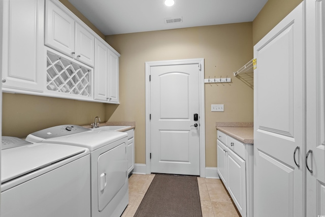 washroom featuring visible vents, light tile patterned floors, washing machine and dryer, a sink, and cabinet space