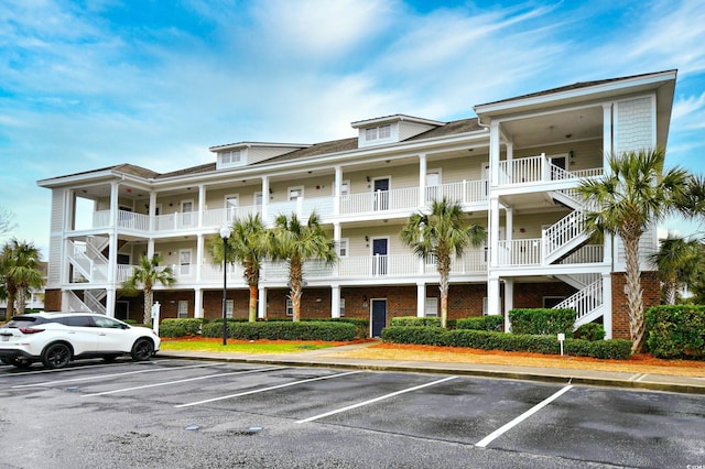 view of apartment building / complex with uncovered parking and stairs
