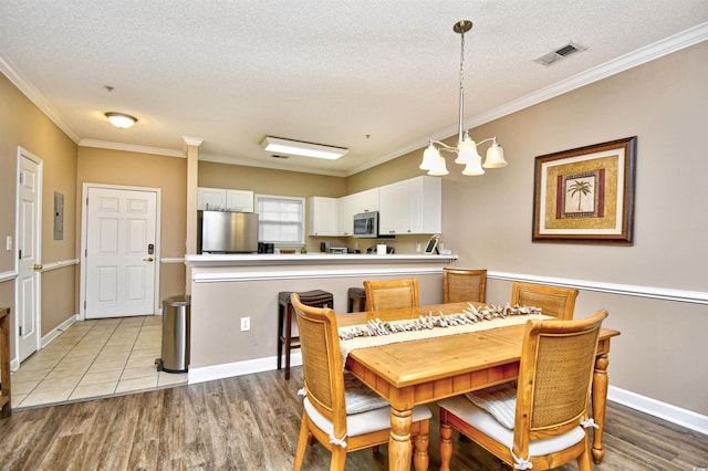 dining room featuring a chandelier, crown molding, light wood-style flooring, a textured ceiling, and electric panel