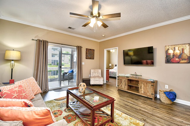 living room with wood finished floors, a ceiling fan, a textured ceiling, crown molding, and baseboards