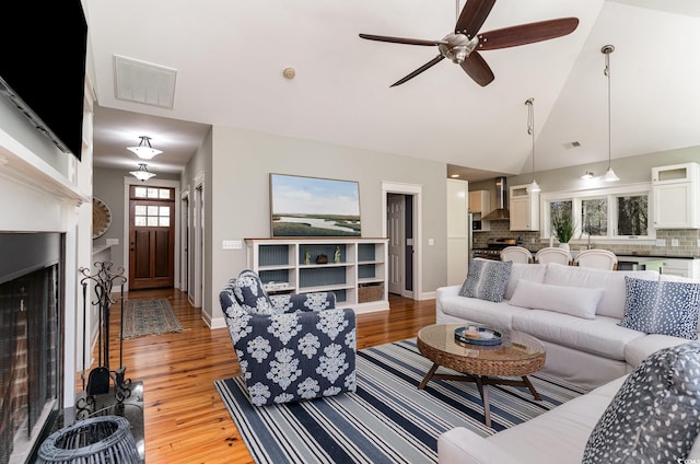 living area with lofted ceiling, ceiling fan, visible vents, and light wood finished floors