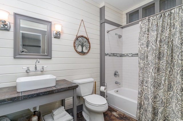 full bath featuring toilet, shower / bath combo with shower curtain, wood walls, and vanity