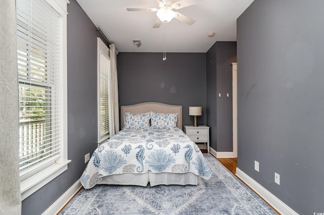 bedroom with baseboards, visible vents, wood finished floors, and a ceiling fan