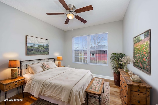 bedroom with a ceiling fan, baseboards, and light wood finished floors