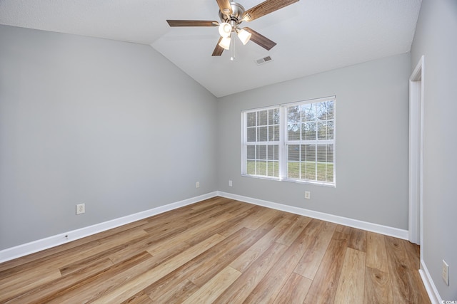 unfurnished room featuring light wood-style flooring, a ceiling fan, baseboards, vaulted ceiling, and visible vents
