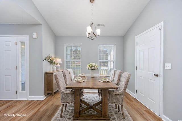 dining area featuring light wood-style floors, baseboards, visible vents, and a notable chandelier