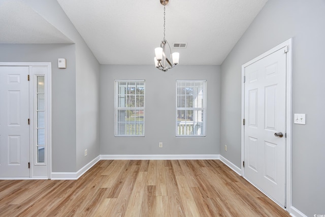 unfurnished dining area featuring baseboards, visible vents, light wood-type flooring, and a chandelier
