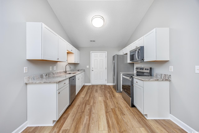 kitchen with appliances with stainless steel finishes, a sink, and light wood-style floors