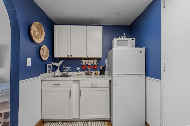6803 N Ocean Blvd Unit 203, Myrtle Beach, SC 29572 - kitchen with white appliances, light countertops, white cabinetry, and a wainscoted wall
