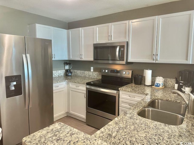 3500 N Ocean Blvd Unit 1203, North Myrtle Beach, SC 29582 - kitchen with stainless steel appliances, white cabinets, wood finished floors, and light stone counters