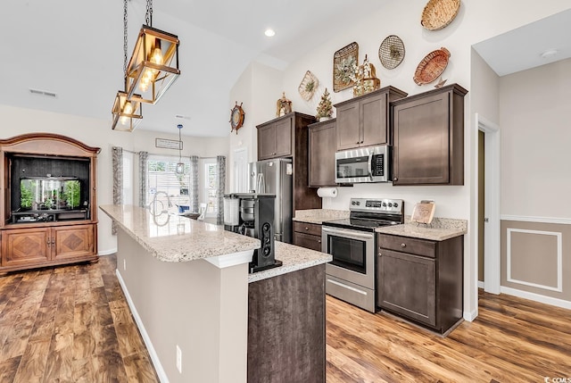 508 Loblolly Ln, Loris, SC 29569 - kitchen featuring appliances with stainless steel finishes, dark brown cabinets, light wood-style flooring, a center island with sink, and lofted ceiling