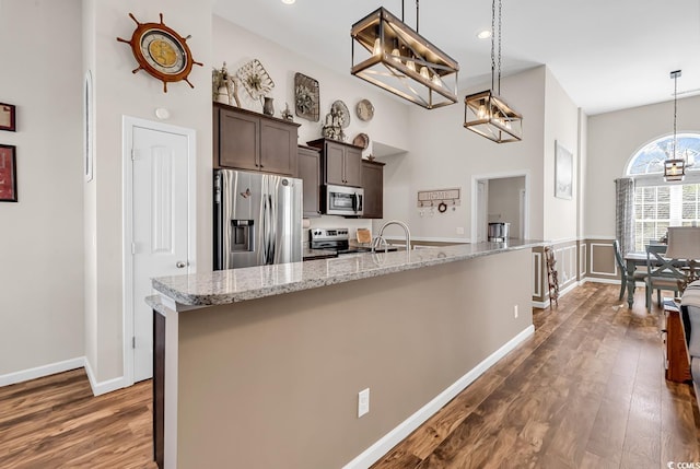 508 Loblolly Ln, Loris, SC 29569 - kitchen with stainless steel appliances, dark wood-type flooring, dark brown cabinets, a chandelier, and light stone countertops