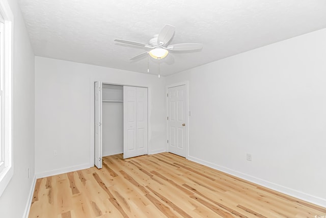unfurnished bedroom with a closet, light wood-style flooring, baseboards, and a textured ceiling