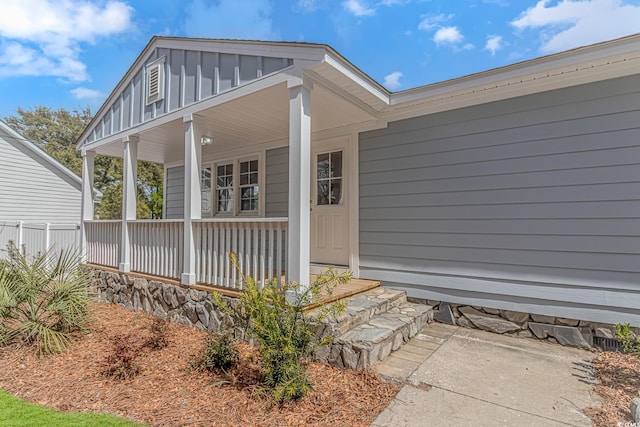 view of exterior entry with board and batten siding and covered porch
