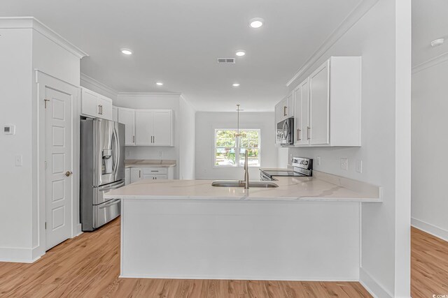 kitchen with a peninsula, white cabinets, visible vents, appliances with stainless steel finishes, and a sink