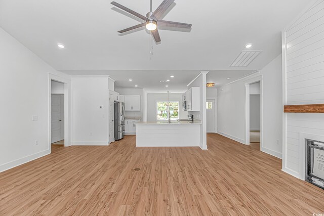 unfurnished living room with light wood-style floors, baseboards, a ceiling fan, and visible vents