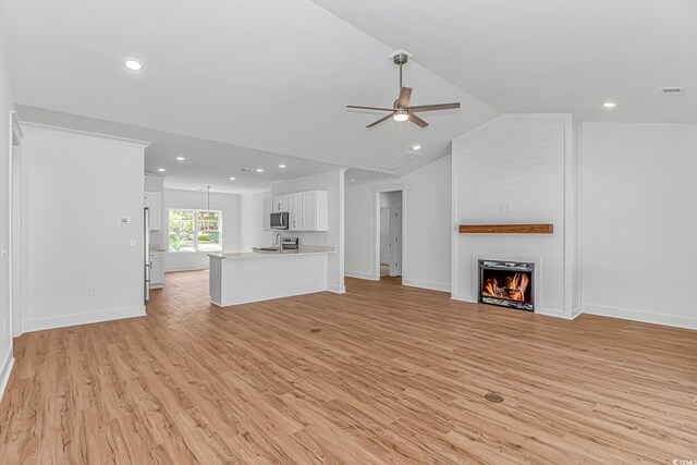 unfurnished living room with a ceiling fan, vaulted ceiling, light wood-style floors, and a fireplace