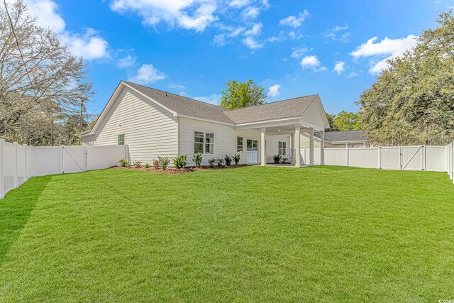 rear view of house with a yard, a fenced backyard, and a gate