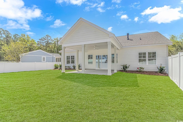 back of property with ceiling fan, a yard, a fenced backyard, a patio area, and a shingled roof