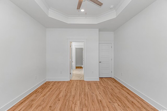 unfurnished bedroom featuring crown molding, ceiling fan, light wood-style flooring, a raised ceiling, and baseboards