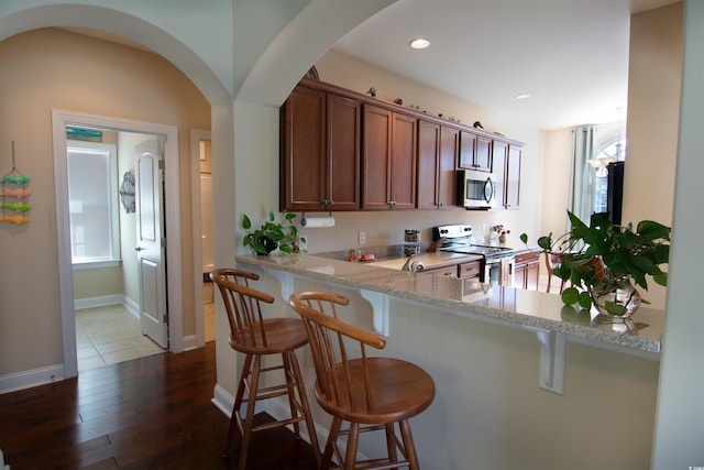 408 7th Ave S, North Myrtle Beach, SC 29582 - kitchen with stainless steel appliances, arched walkways, a kitchen bar, dark wood finished floors, and recessed lighting