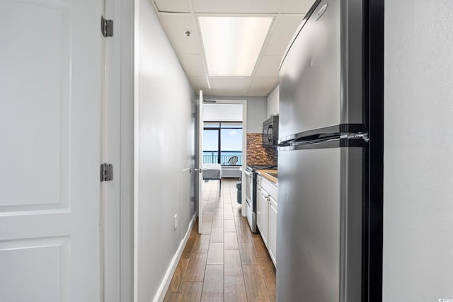 6804 Ocean Blvd N Unit 1529, Myrtle Beach, SC 29572 - kitchen with baseboards, backsplash, white cabinets, appliances with stainless steel finishes, and wood finished floors