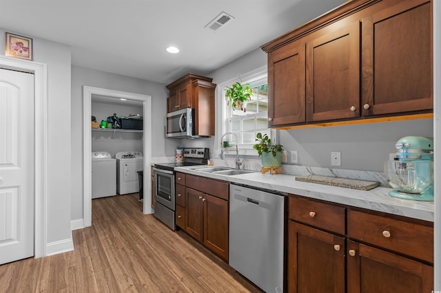 1524 Stilley Cir, Conway, SC 29526 - kitchen with stainless steel appliances, separate washer and dryer, a sink, light wood-style flooring, and light stone countertops