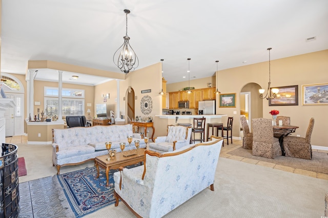 living room with arched walkways, a notable chandelier, light carpet, and baseboards